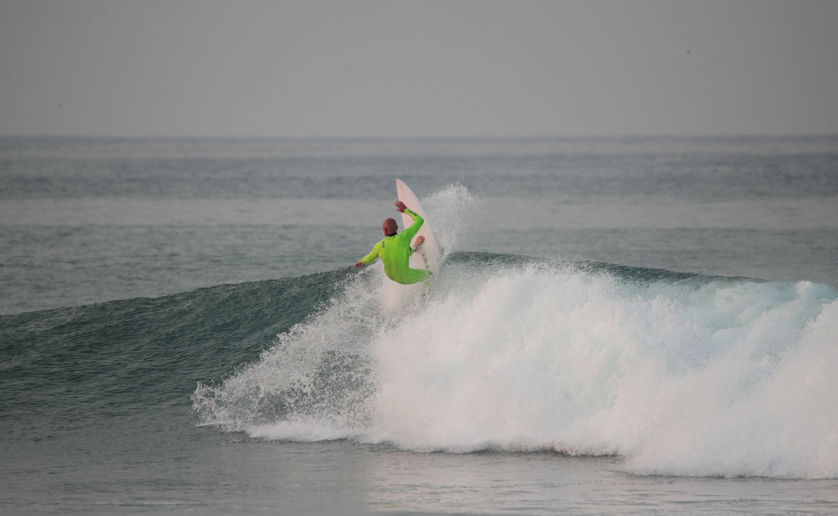 Man surfing a wave in a fluorescent lime Xcel Comp wetsuit