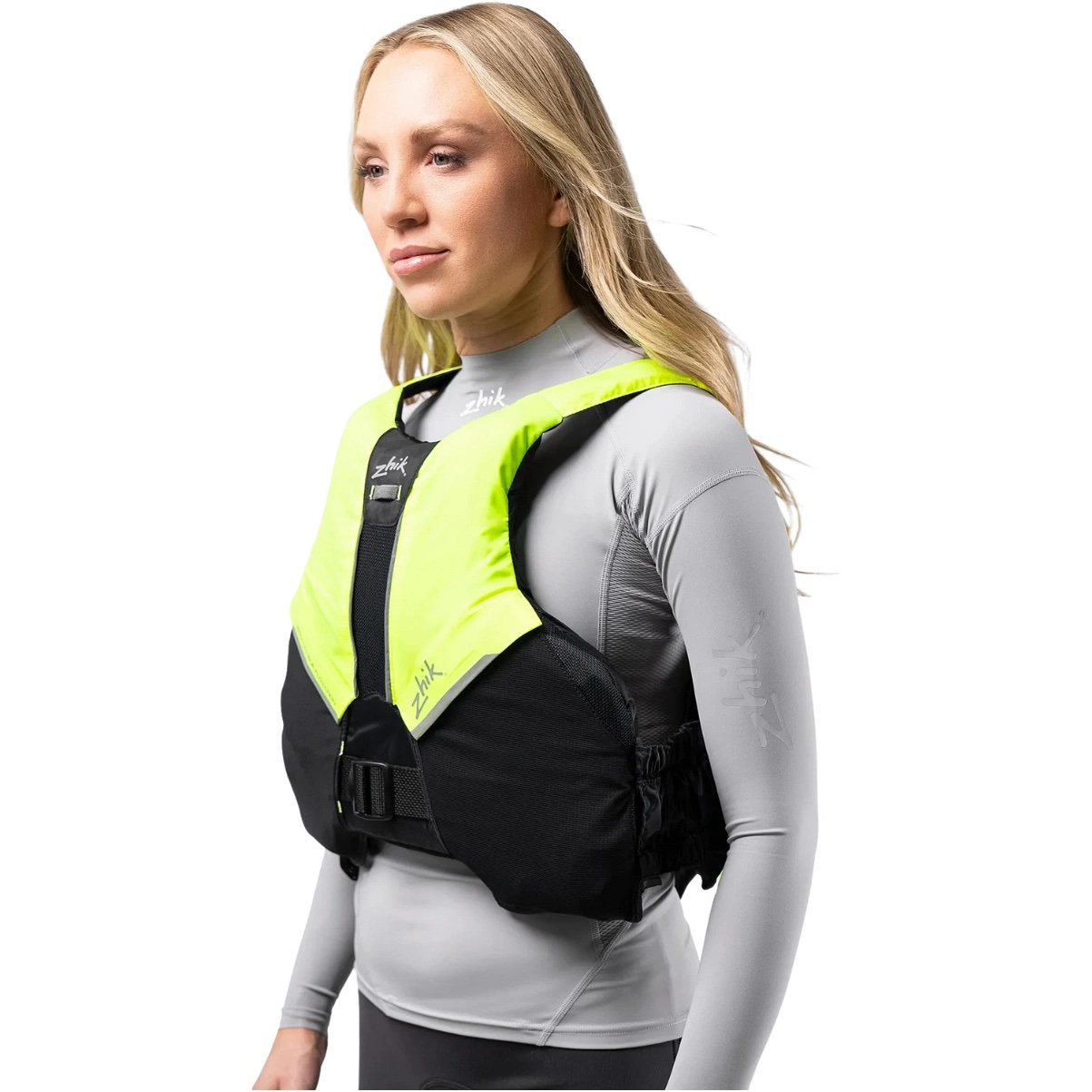 Woman wearing a fluoro yellow Zhik buoyancy aid over a grey rash top, side view showing the fit